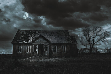 Old wooden house,dramatic clouds at night. Abandoned Haunted Horror House.Near is one tree at night...