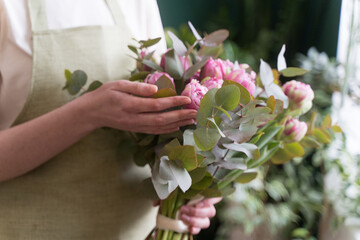 Professional florist checks a beautiful bouquet before sending it to the customer. Fresh flowers in the hands of a young woman close-up. The concept of small business and women entrepreneurs