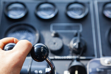 Black luxury yacht control panel out of focus, with speed control levers on which the human hand.