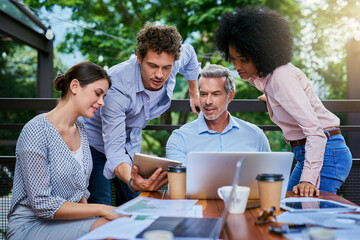 Doing business whenever and where it needs to be done. Shot of a group of colleagues having a meeting at a cafe.