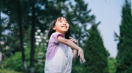Fototapeta premium Image of Asian little girl playing with soap bubbles at park