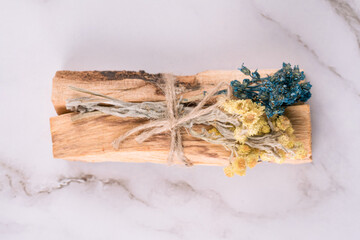 Top view on palo santo sticks with bouquets of dried flowers on white marble table background. Holy...