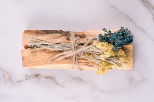 Top view on palo santo sticks with bouquets of dried flowers on white marble table background. Holy wood sticks for meditation and spiritual practices concept. Mental health