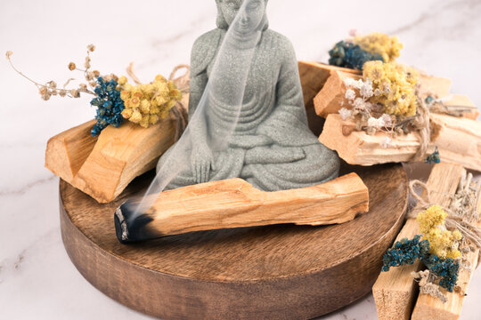 Incense burning. Burning palo santo sticks with Buddha statue in a meditation room on white marble table background. Zen concept, meditation and spiritual practices
