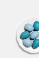 Dyed Easter eggs pastel colors blue, gray, beige on round white plate. Happy Easter holiday concept, celebration food, decorated chicken egg, neutral trendy colored card. Top view table