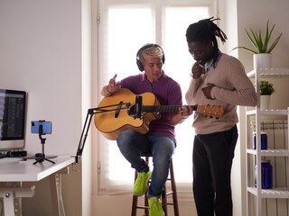 A personal afroamerican tutor explains to his asian student how to play studied chord correctly....