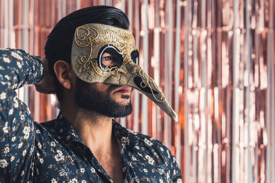 bearded man in traditional Venice mask with big nose medium closeup indoors carnival concept. High quality photo