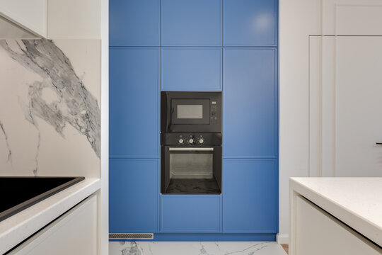 blue cabinet in the white kitchen with black oven