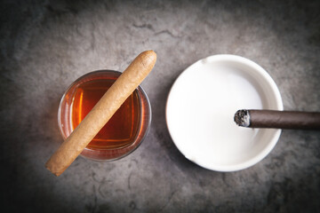 Glass of whisky, ashtray and cigar on the table.