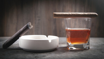 Glass of whisky, ashtray and cigar on the table.