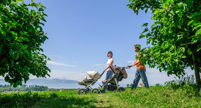 Elternpaar mit dem Nachwuchs im Kinderwagen beim Spaziergang nahe des Bodensees
