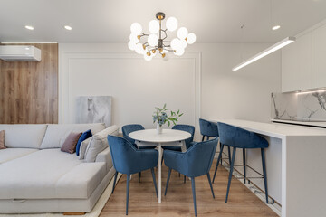 direct view of the guest room with dining table, white kitchen with blue furniture and wood elements