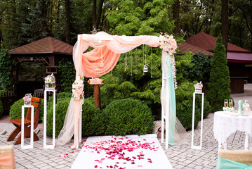 Arch for the wedding ceremony. Arch, decorated with beautiful fresh flowers and cloth. Registration at the place of marriage. Wedding arch of real flowers.