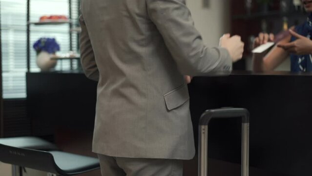 Unrecognizable business passenger walking to the lounge in the airport terminal and asking for a drink.