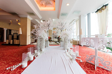 Arch for the wedding ceremony, which is decorated with floral compositions and a pink cloth and candles in rustic style.