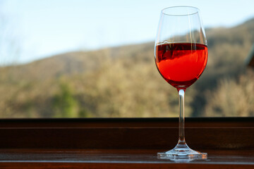 Glass of red wine stands on wooden windowsill