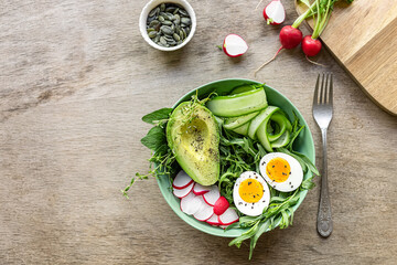 Summer healthy food. Green keto salad with eggs, avocado, radish, and cucumbers. Copy space for text or recipe.
