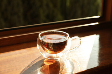 Cup of tea stands on wooden windowsill