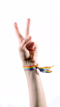 Hand wearing a bracelet with the colors of the LGBT flag showing two fingers as a symbol of peace or victory. LGBT symbol. Vertical video.