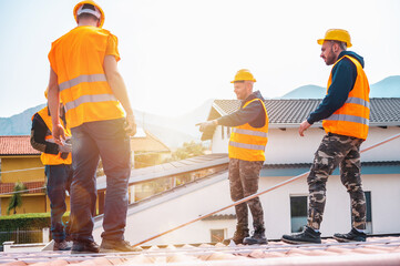 Team of technical workers work on the roof of a house - obrazy, fototapety, plakaty