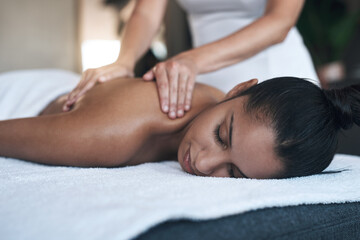 You deserve this and more. Shot of a young woman getting a back massage at a spa.