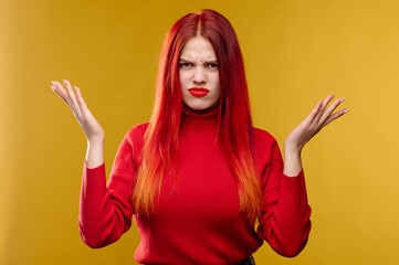 Young woman with red hair holding head by hands on yellow background