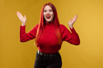 Young pretty woman with red hair and red sweter posing on yellow background