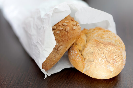 fresh crispy bread rolls in paper bag on brown table