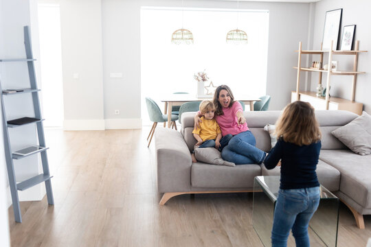 Cheerful mother playing with children in living room