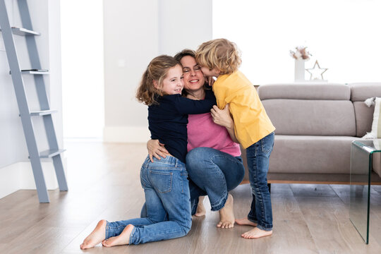 Children kissing mother in living room