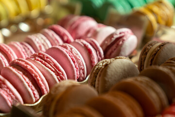 Assortment of colorful french macaroons on cafe showcase for sale . Variety of macaron flavours. Sweet almond cakes in store. Cookies in the shop on storefront