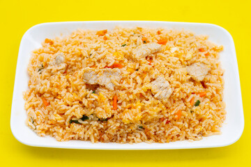Fried rice in white plate on yellow background.