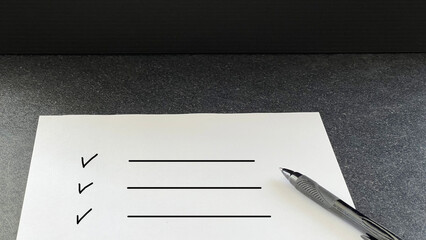 黒いテーブルの上のチェックリストの白い用紙とペン