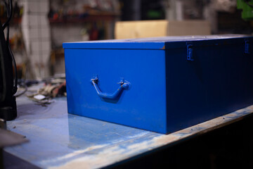 Tool box in blue. An old box lies on the table. Vintage object in the garage.
