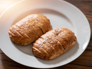 Serving of two ham and cheese pies on a white plate on wooden table. Simple food concept. Pastry product for lunch.