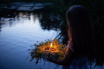 Girl with ritual wreath going to the river late in the evening. Ivan Kupala celebration, ritual wreath with burning candle