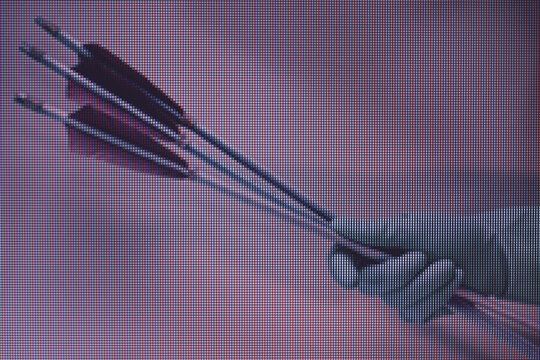 Beautiful hand holding old green arrows in the color light. Beautiful old arrow minimal in neon light. Minimalism retro style concept. Macro  photography view. Close-up of pixel.