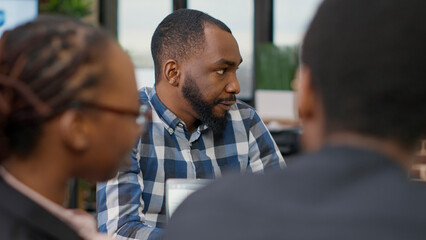 Business man talking to colleagues at boardroom meeting, doing teamwork to create financial strategy for company development. Male worker meeting with people in office. Handheld shot.