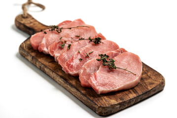 Raw pork sliced meat on wooden board on white background with dry basil leaves and spice. fresh raw...