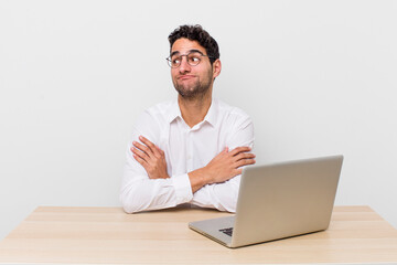 hispanic handsome man shrugging, feeling confused and uncertain. businessman and desk concept - obrazy, fototapety, plakaty