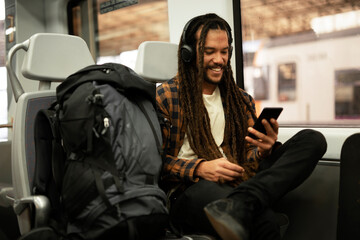Young man listening the music while traveling by a train. Handsome young man traveling by a train.