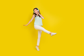 Fototapeta na wymiar Full size photo of cheerful pretty female dancing go on walk listening her favorite music isolated on yellow color background