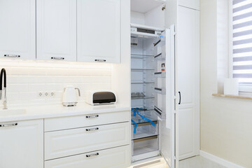 new open refrigerator in the white kitchen with backlight