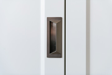 metal dark handle in a white wooden cabinet door