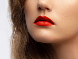 Fototapeta premium Cosmetics, makeup and trends. Bright lip gloss and lipstick on lips. Closeup of beautiful female mouth with red and pink lip makeup. Beautiful part of female face. Perfect clean skin