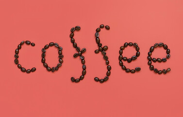 Text COFFEE made of Roasted Coffee beans top view on pink background
