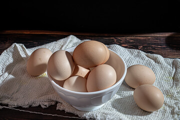 Close-up of raw chicken eggs in a white cup on a dark background