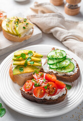 Fresh crostini on rye and wheat bread with feta, ricotta, vegetables, fruits and fresh herbs.
