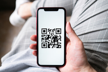 Young man in modern cafe showing smartphone scan QR code for payment 
