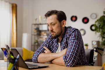 A thoughtful boy sits with his arms folded in front of his computer, contemplating his newly assigned task. The man wonders how best and fastest to complete it.